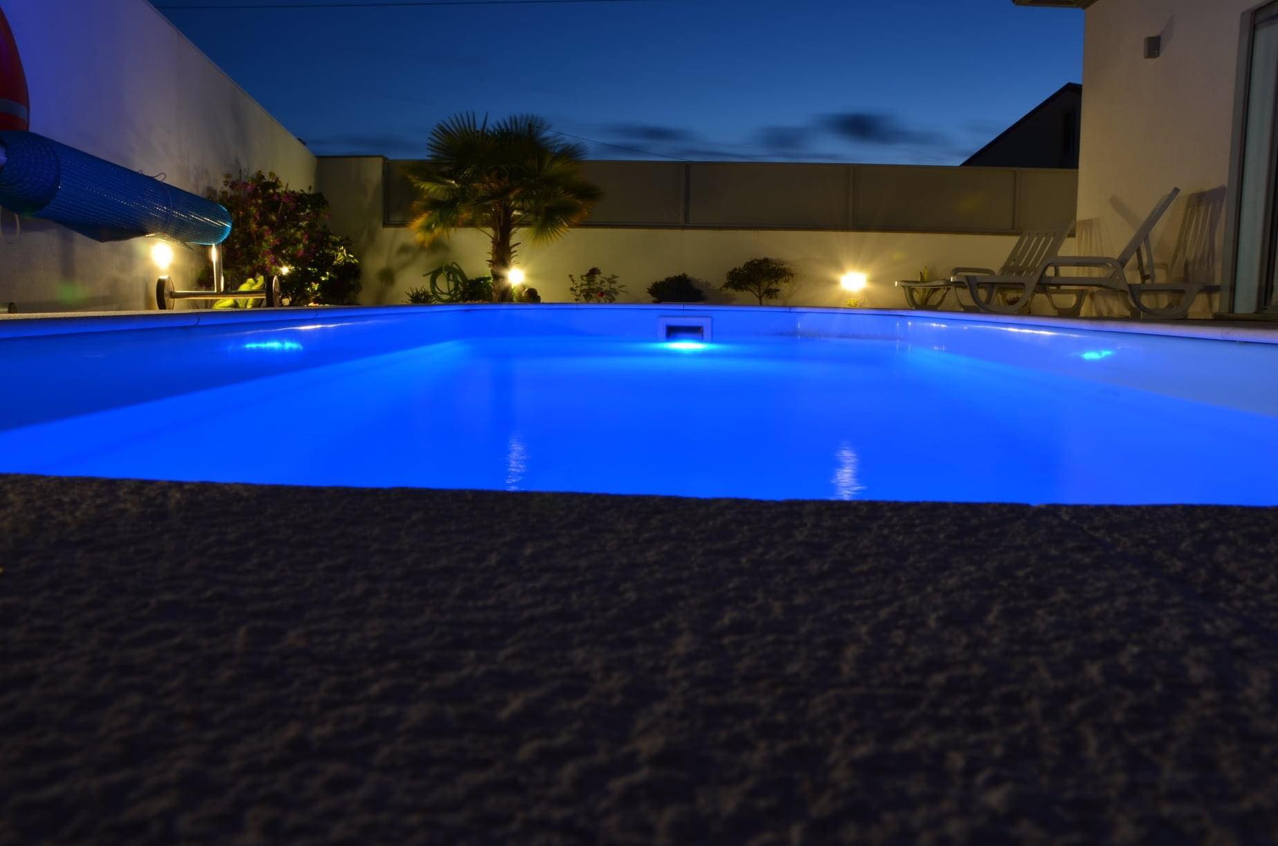 Foto da piscina á noite com as luzes 